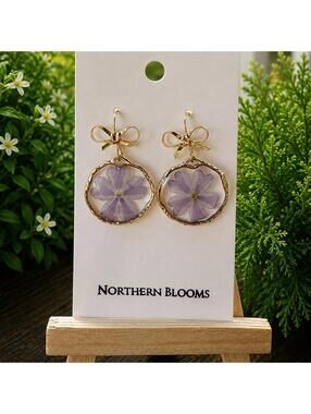 Purple pressed flowers in gold round setting with bow accents